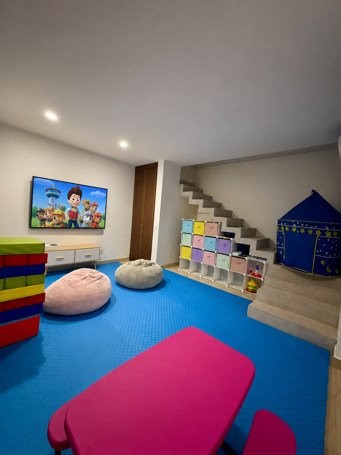 Sala de cine y videojuegos para niños en la ludoteca Ludo Mix, con pantalla, pufs y área de descanso