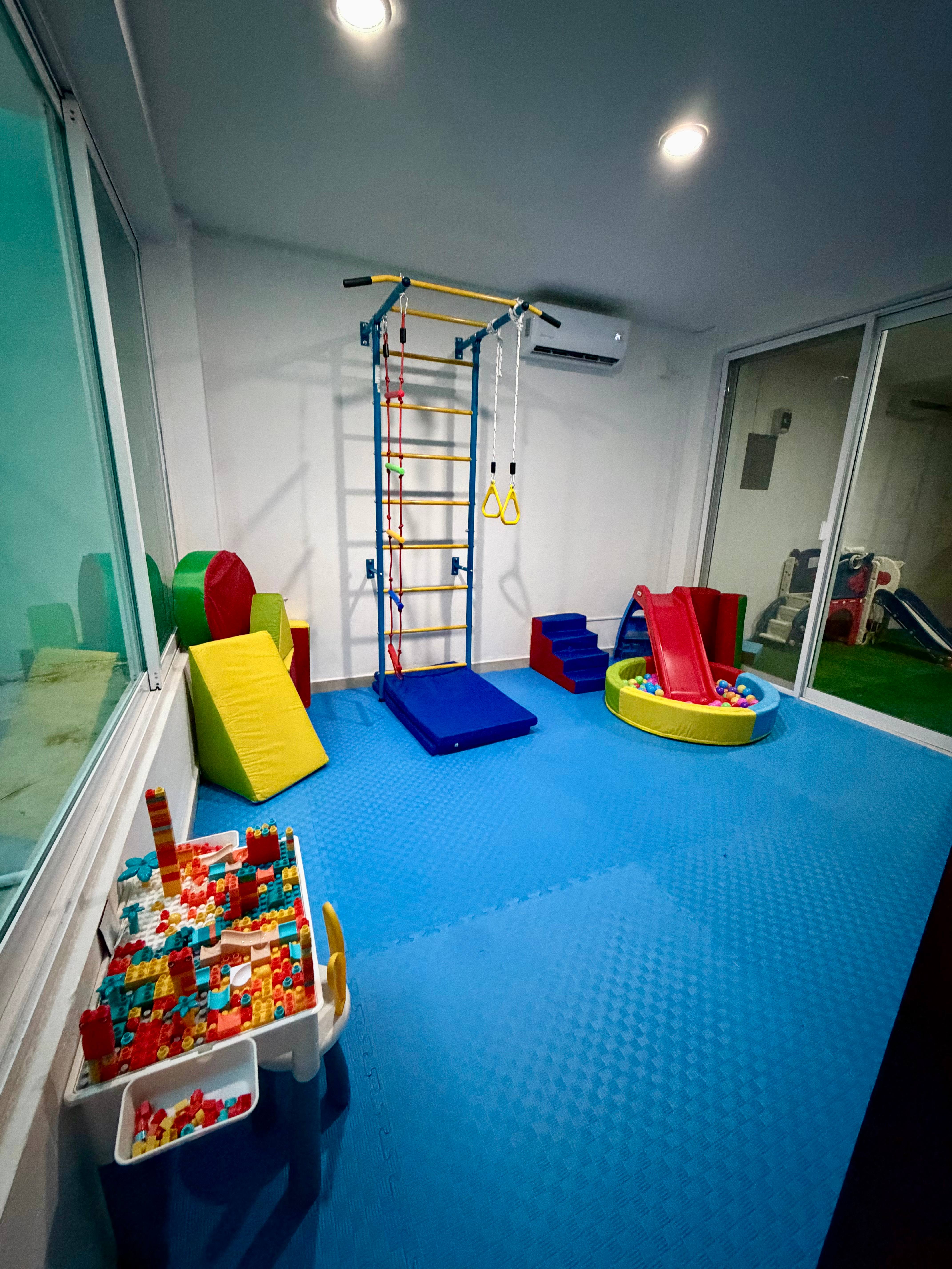 Zona de movimiento de la ludoteca Ludo Mix en Puerto Vallarta, con escalera sueca, tobogán, piscina de pelotas y área de pasto sintético